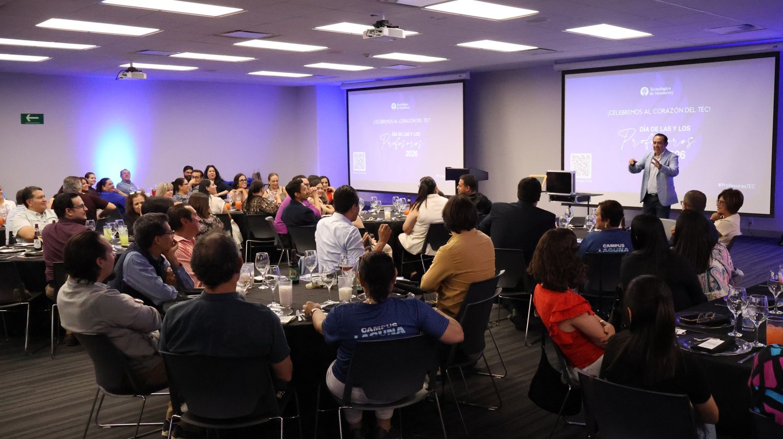 Salón de un evento corporativo con mesas y pantallas durante una conferencia